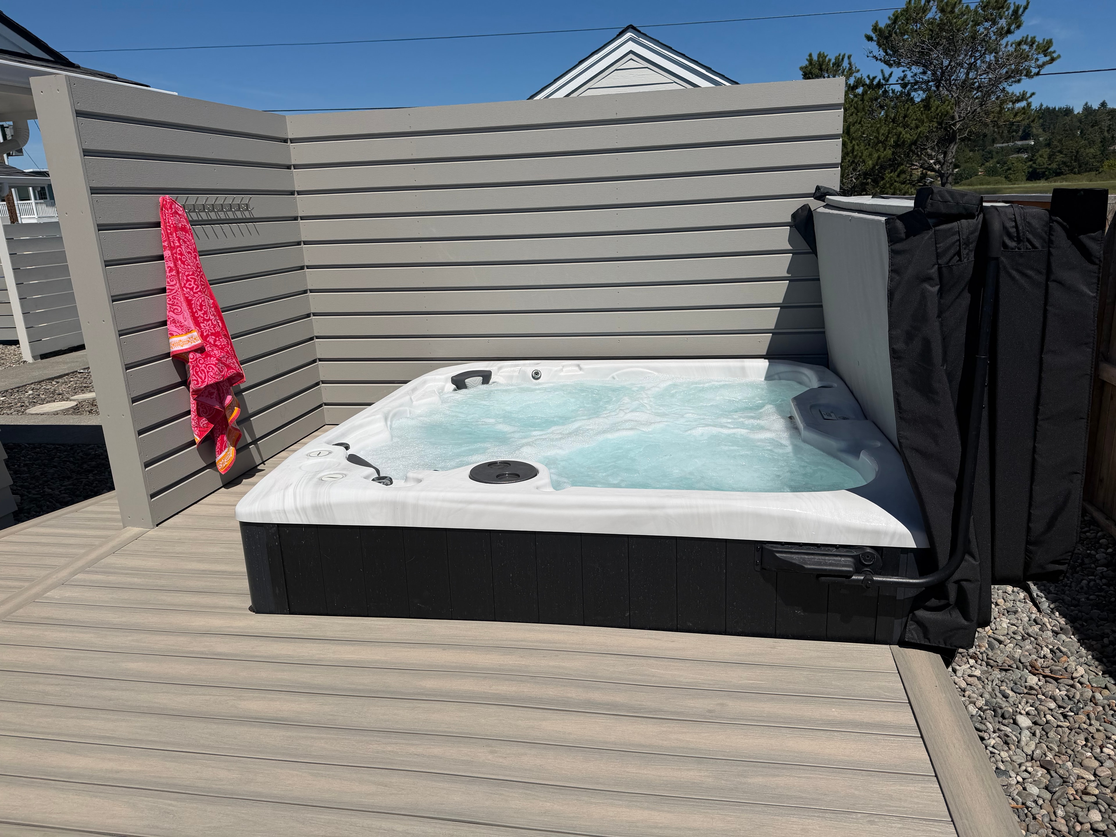 Hot tub on waterfront deck with open water and blue sky